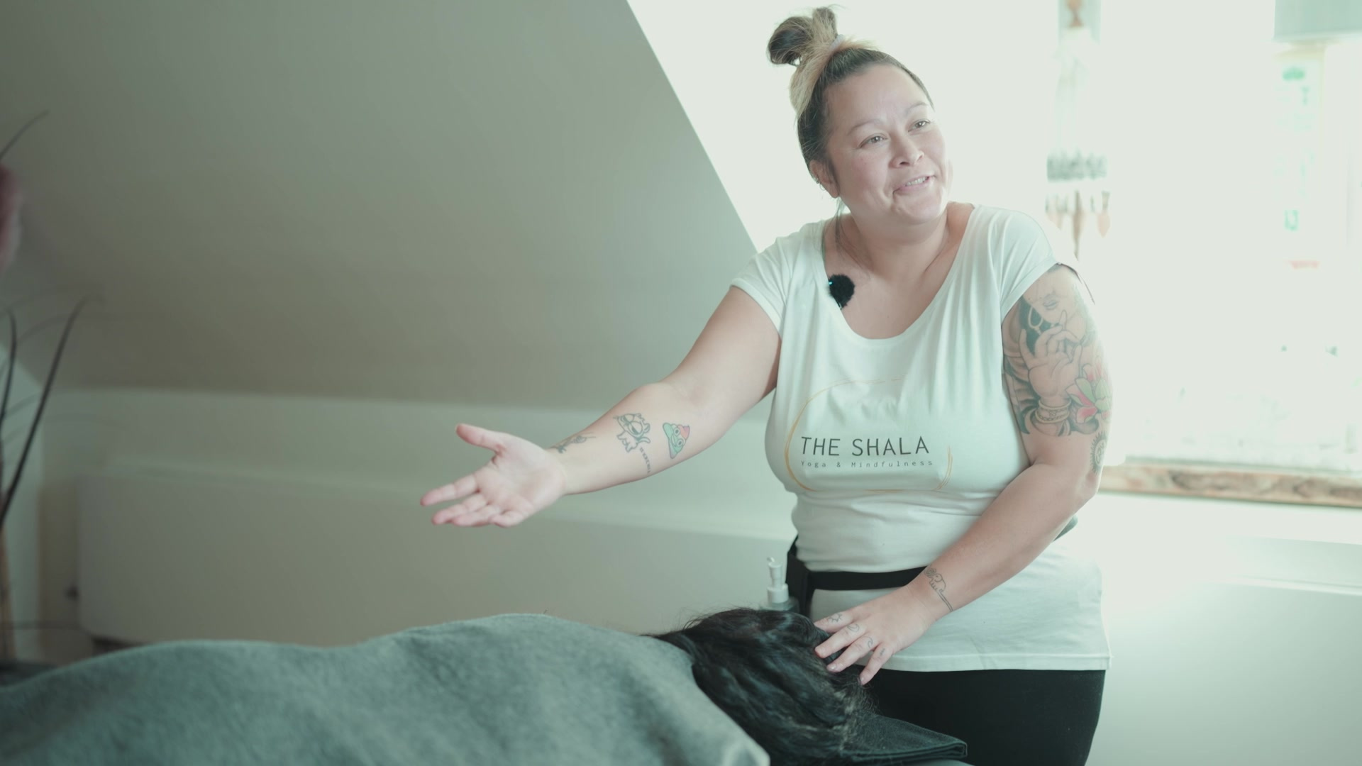 Tanja forklarer en massasjeteknikk ved hodet på en person som ligger på massasjebenken.